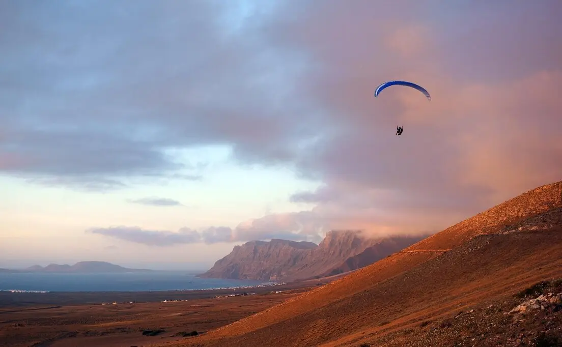 Erleben Sie das atemberaubende Paragliding in Famara, Lanzarote, wo der Himmel und das Meer in einem spektakulären Farbenspiel verschmelzen. Die beeindruckenden Klippen und die sanften Winde bieten ideale Bedingungen für sowohl Anfänger als auch erfahrene Gleitschirmflieger.